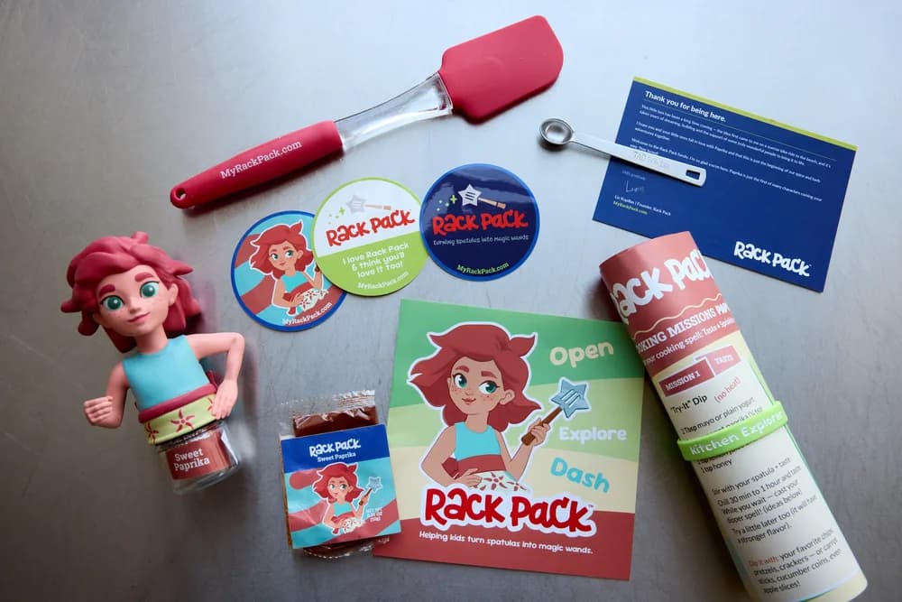 The Rack Pack kit laid out: Paprika's figurine, a spatula, stickers, the founder's note, and a spice jar